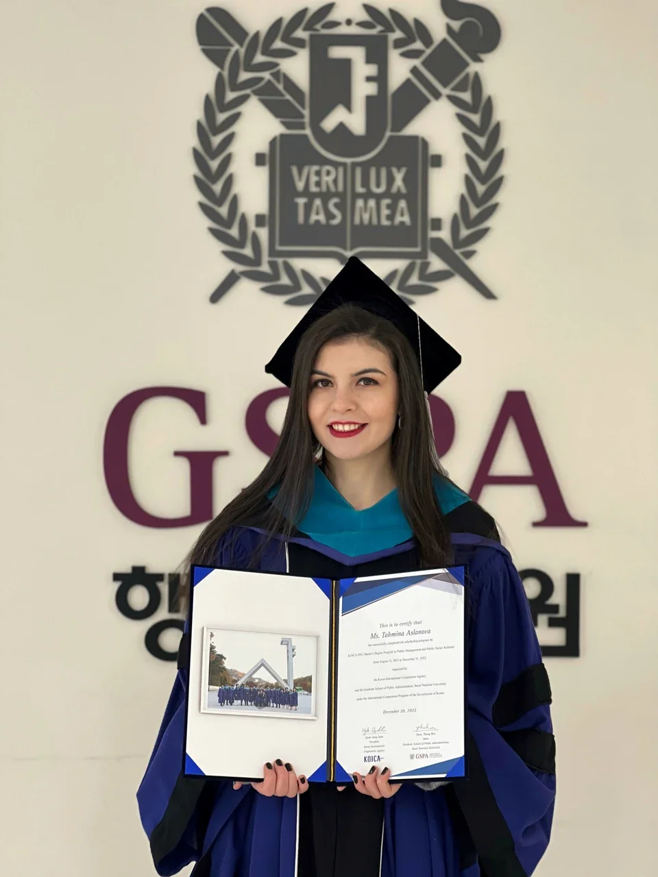 Tahmina in graduation robes, holding her certificate at Seoul National University.